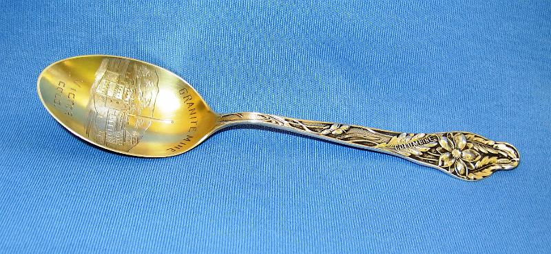 Souvenir Mining Spoon Granite Mine Victor.JPG - SOUVENIR MINING SPOON GRANITE MINE VICTOR COLORADO - Sterling silver spoon, 5 1/2 in. long, engraved mining scene in gold washed bowl with engraved GRANITE MINE VICTOR COLO. in bowl, ca. 1900, handle marked with floral pattern and COLUMBINE, back with sterling marking and F Co hallmarks for Fessenden & Co, Providence, RI  [Partners Charles L. Tutt, Spencer Penrose and Charles M. MacNeill purchased the Gold Coin Mine in the center of Victor, Colorado in 1902 and renamed it the Granite Mine. The Woods family, founders of Victor and the previous owners, struck a rich vein of gold while excavating for the foundation of a hotel at 4th & Victor Avenue in 1894.  This vein became the Gold Coin Mine, one of the richest mines in the Cripple Creek District.   With this stroke of luck and fortune, the hotel was built at a new location.  The Granite Gold Mining Company was organized by the partners in 1905 with the Granite Mine as one of their primary holdings including the Gold Coin shaft.  By 1919, machinery in the Gold Coin shaft was dismantled as most of the ore had been extracted.  Remnants of the mine, as well as the Gold Coin Club built for the mine’s workers, have been preserved and can still be seen in Victor. The old hotel burned in the big fire of 1899, when Victor’s entire business district was leveled in one August afternoon.]